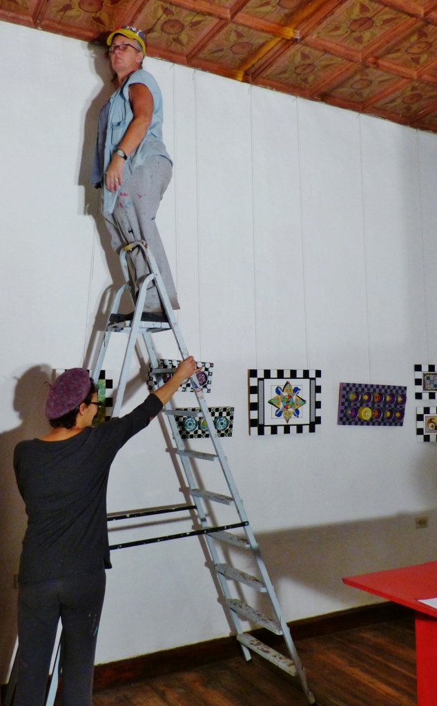 Kathy hanging her art for an exhibit at friend Laura's (holding ladder) creative space called Fishbon del Sur-